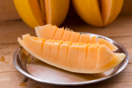 Closeup to split the orange melon on wood plateの写真素材