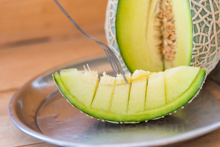 Closeup to green melon on wood plateの写真素材