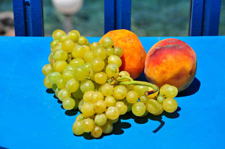Green grapes and peachs on blue tableの写真素材