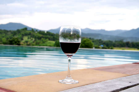 Glass of wine by the pool with bueatiful mountain view の写真素材