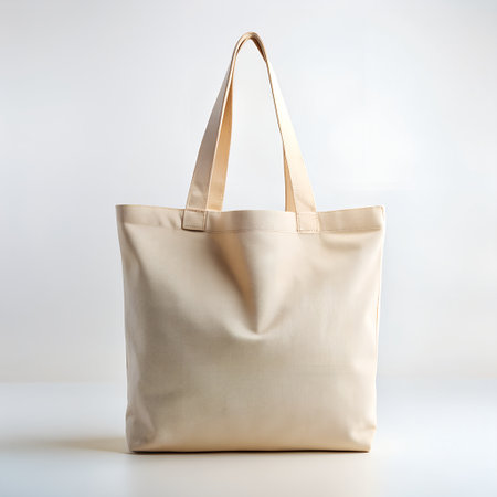 A plain beige canvas tote bag with beige handles, isolated on white backgroundの素材