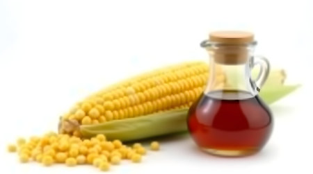 Corn oil in a glass bottle with corn cob and kernels isolated on white backgroundの素材