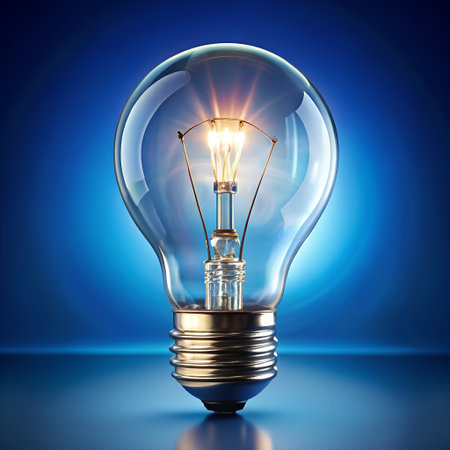 A closeup, studio shot of a clear glass incandescent light bulb glowing brightly with a warm yellow filament against a dark blue gradient backgroundの素材