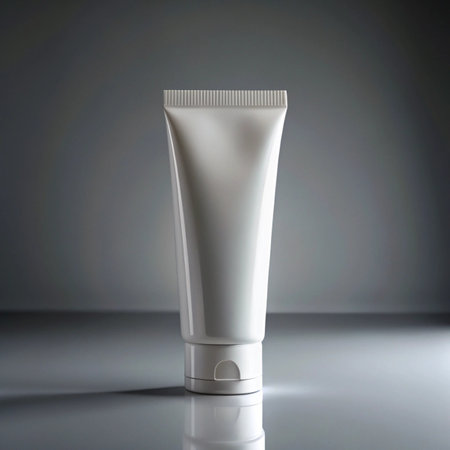 White cosmetic tube with cap, studio shot with dramatic lighting and reflective surface, ideal for beauty and skincare product presentationの素材