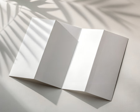 Blank folded brochure or leaflet with soft shadows and light, ready for graphic design and branding mockupの素材