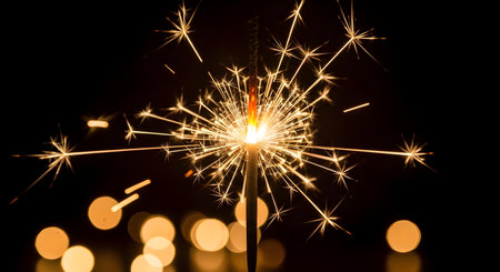 A vibrant sparkler burns brightly in the dark, creating a dazzling display of light and sparks, with soft bokeh lights in the background, perfect for festive eventsの素材