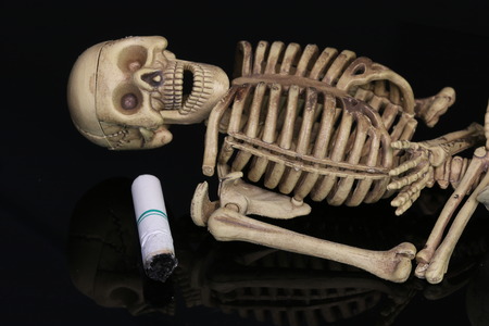 Three human skeletons with cigarettes.の写真素材