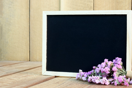 Blackboard with flowers on wooden floorの写真素材