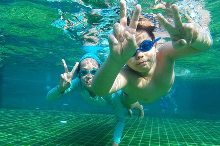 Boys and girls in Asia are diving in the pool, having fun.
