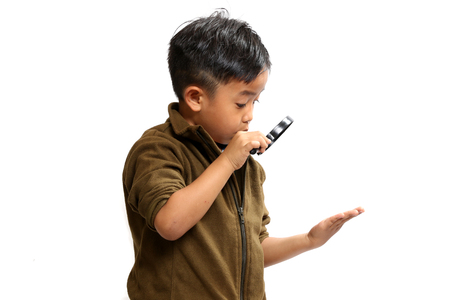 Asian boy using a hand magnifying glass on a white background.の写真素材