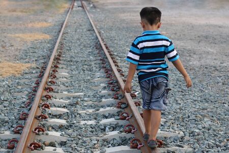 Boy walking on railroad tracksの写真素材