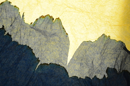 Blue paper burning on the edge of the yellow paper for pattern background.の写真素材