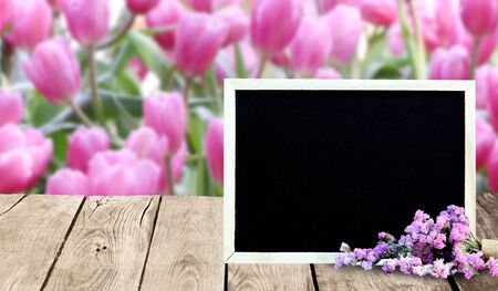 Blackboard frame on the wooden floor with a background as a flower.の写真素材