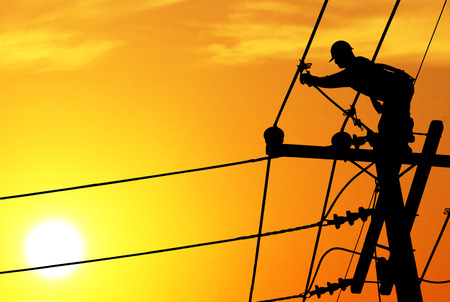 Shadow electricians repairing wire on electric power pole at the sunset blurの写真素材