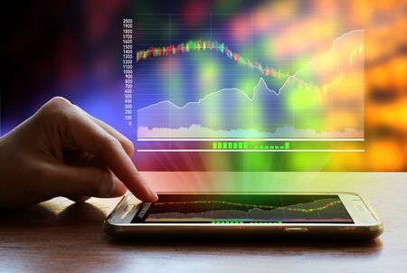 Woman hand using smartphones to monitor investment in the stock market.の写真素材