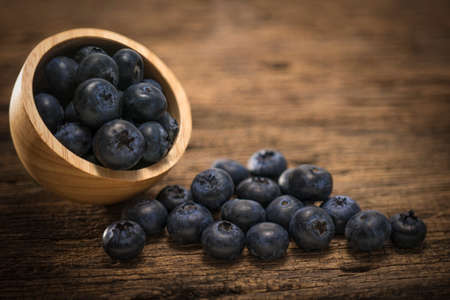 Fresh Blueberries in wooden bowl on the wooden table, Sweet Blueberry raw berries on wood background.の写真素材