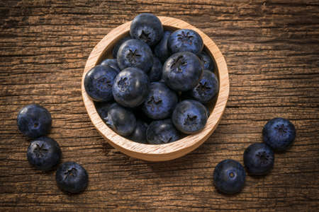 Fresh Blueberries in wooden bowl on the wooden table, Sweet Blueberry raw berries on wood background.の写真素材