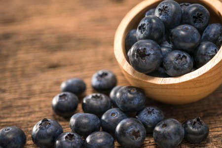 Fresh Blueberries in wooden bowl on the wooden table, Sweet Blueberry raw berries on wood background.の写真素材