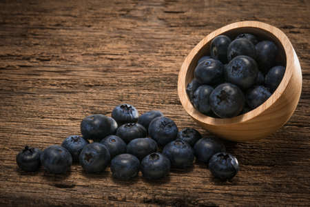 Fresh Blueberries in wooden bowl on the wooden table, Sweet Blueberry raw berries on wood background.の写真素材