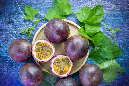 Fresh Passion fruit with slice in wooden plate, Purple Passion fruit or Maracuya with leaf on a wooden table.の写真素材