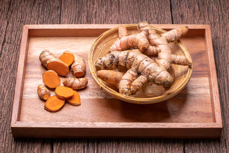 Turmeric root and sliced in wooden plate, Table top view Curcuma Longa Linn or rhizome root on a wooden table background.の写真素材