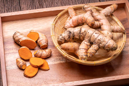 Turmeric Powder and Turmeric root in wooden plate, Curry Powder on a wooden table background.の写真素材