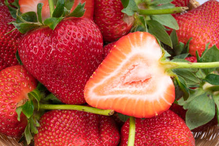 Red Strawberries in wooden bowl on wooden table, Fresh long stem berries, Organic Strawberry in Bamboo basket.の写真素材