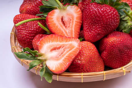Red Strawberries in wooden bowl on wooden table, Fresh long stem berries, Organic Strawberry in Bamboo basket.の写真素材