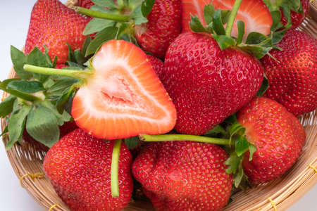 Red Strawberries in wooden bowl on wooden table, Fresh long stem berries, Organic Strawberry in Bamboo basket.の写真素材