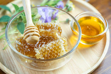 Sweet Honeycomb in wooden plate on wooden background, Yellow Honeycomb on wooden table.の写真素材
