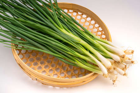 Fresh spring onion in bamboo basket isolated on white background, Green onion on White Background.の写真素材