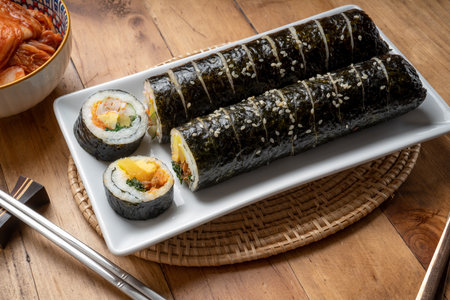 Korean Sushi Rolls or Kimbap is a popular Korean dish in white plate on wooden table, California Maki,  Steamed rice wrapped in seaweed with shrimp eggs meat and vegetable.の写真素材