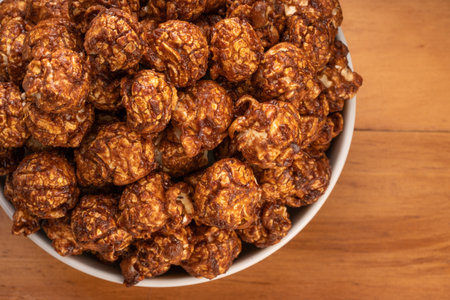 Crispy caramel popcorn in bowl on wooden table, Chocolate Popcorn in a bowl on wooden background. Top view.の写真素材