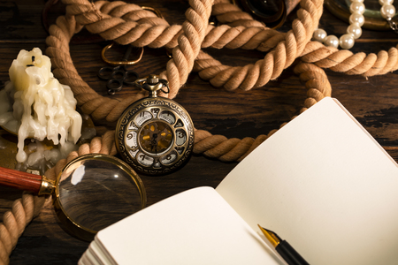 Antique clock on the background of vintage notebook and pen. Blank sheet for writing text.の写真素材