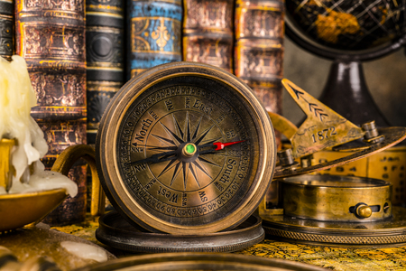 Antique compass on the background of the globe and books. Vintage style. 1565 old map of the year.の写真素材