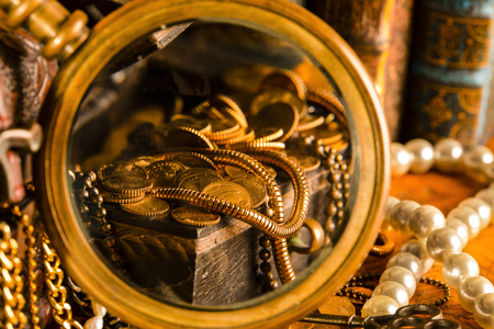 Treasure chests with gold in a magnifying glass. Pearls and gold chains. Vintage style.の写真素材