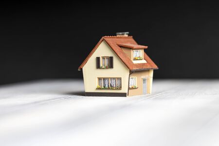 A small copy of the house is on the table on a black background.の写真素材