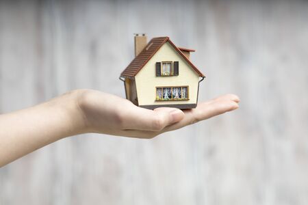 The man in his hands holds a small copy of the house.