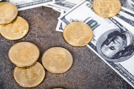 The cryptocurrency Bitcoin coin. Gold coins and packs of hundred dollar bills.の写真素材