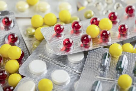 Multi-colored pills and capsules lie on the table. Scattered drugs.
