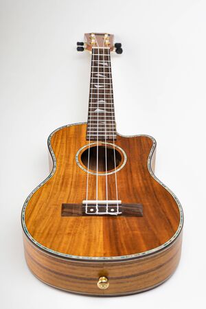 Ukulele on a white background. Hawaiian guitar lies on the table.の写真素材