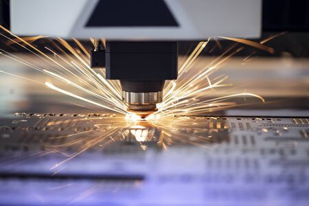 Automated programmed machine. Industrial laser machine cuts out parts in sheet steel. Heat. Sparks during operation of production machine at factory.の写真素材