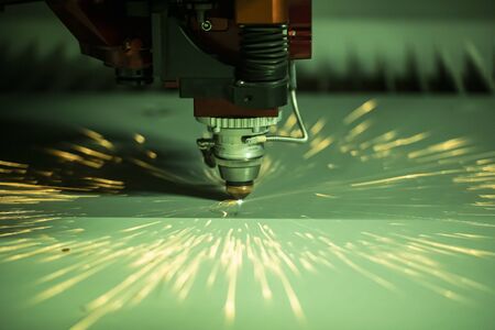 Automated programmed machine. Industrial laser machine cuts out parts in sheet steel. Heat. Sparks during operation of production machine at factory.の写真素材