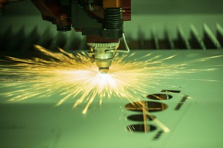 Automated programmed machine. Industrial laser machine cuts out parts in sheet steel. Heat. Sparks during operation of production machine at factory.の写真素材