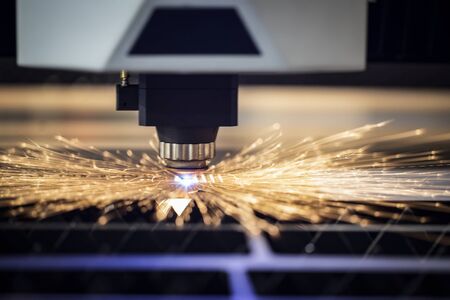 Automated programmed machine. Industrial laser machine cuts out parts in sheet steel. Heat. Sparks during operation of production machine at factory.の写真素材