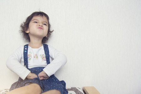 Little girl shows an emotion of mischief, against a white wall backgroundの写真素材