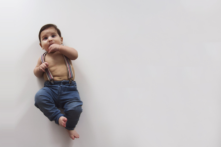 Little cute baby boy in braces lies on white backgroundの写真素材