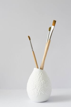 Three art brushes in a white beautiful vase on a white backgroundの写真素材