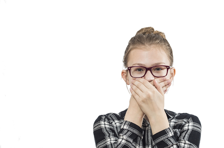 Young beautiful teenage girl wearing glasses, covering her mouth with her hands. On a white background.の写真素材