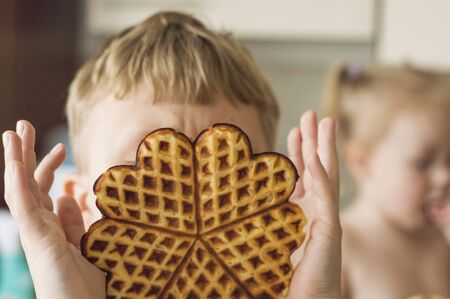 The child eats Belgian waffles. Beautiful girl in crumbs, close-up portrait.の写真素材